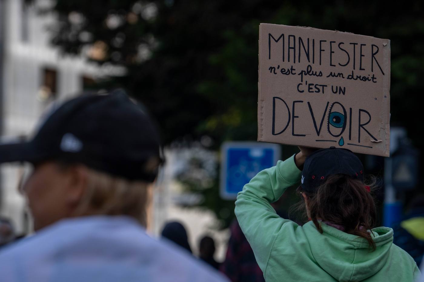 Pancarte « Manifester n’est plus un droit, c’est un devoir » au-dessus de la foule