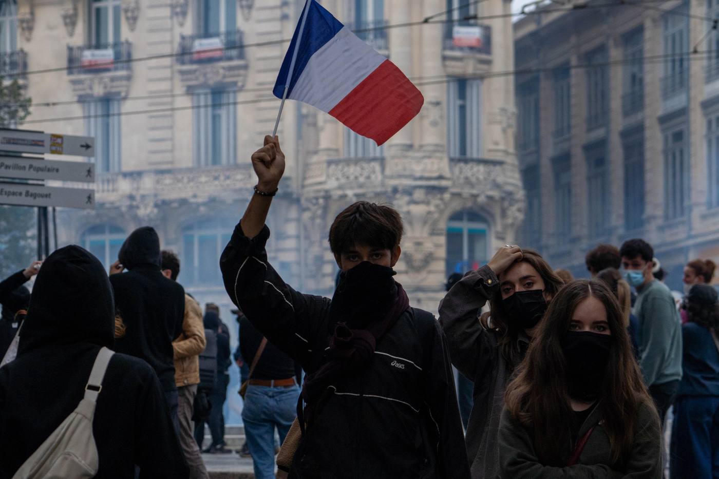 Drapeau français levé au-dessus de manifestants masqués