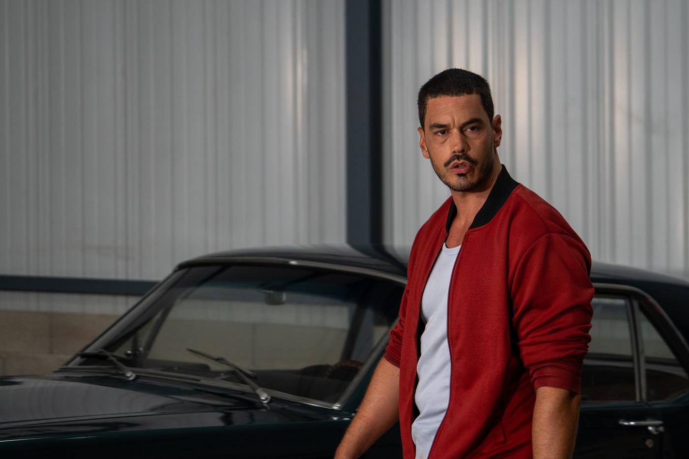 Comédien en veste rouge près d’une voiture ancienne