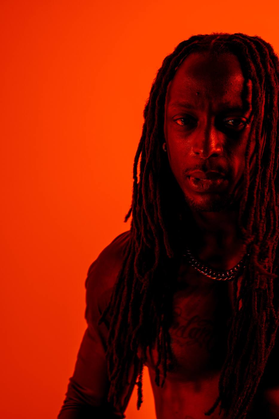 Portrait en clair-obscur d’un homme aux dreadlocks, lumière rouge