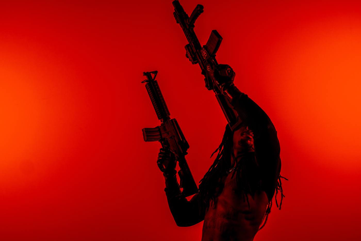 Silhouette brandissant deux fusils sur fond rouge