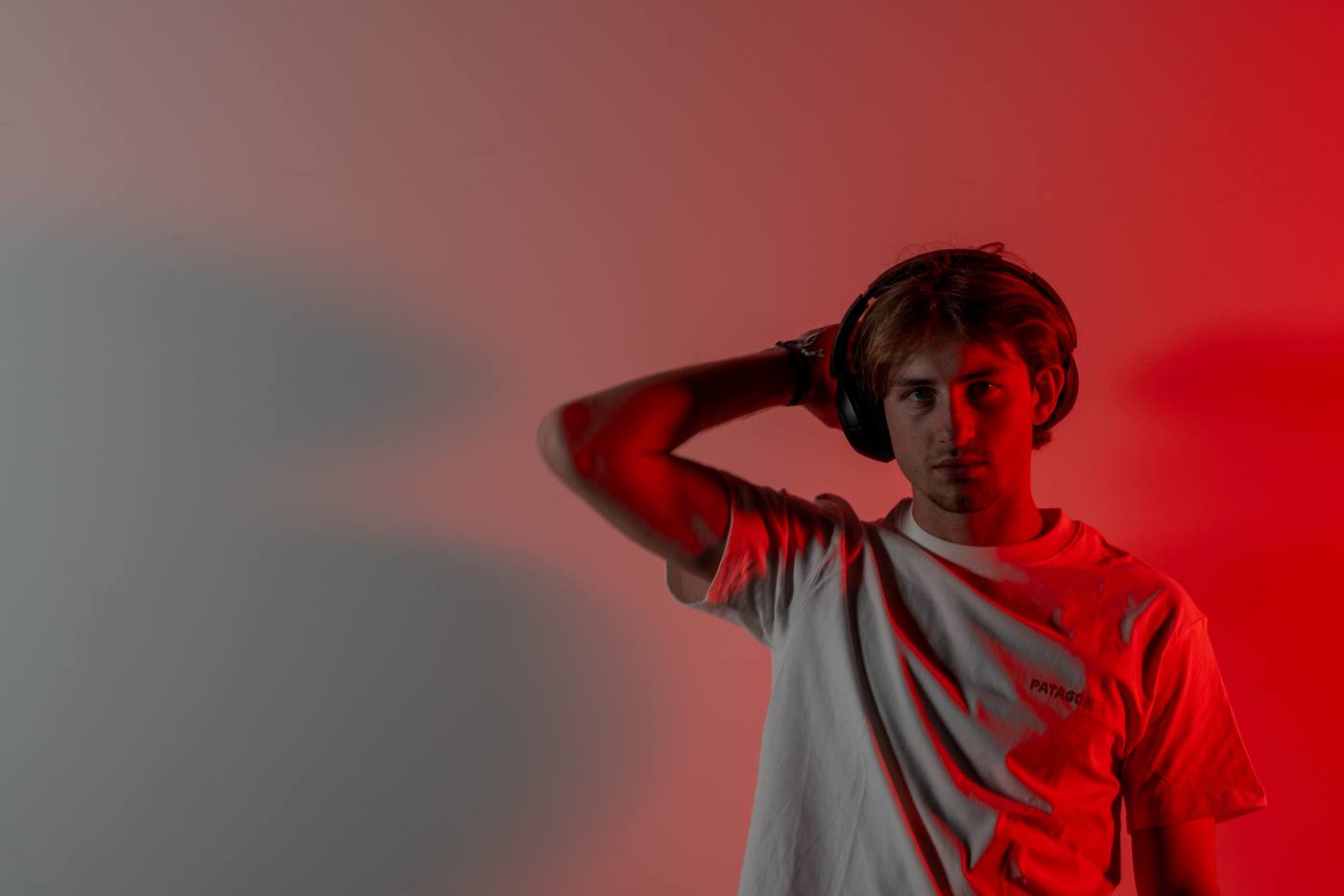 Jeune homme au casque audio, main dans les cheveux, lumière rouge