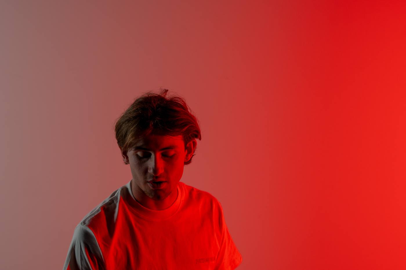 Jeune homme baissant les yeux, t-shirt teinté de rouge