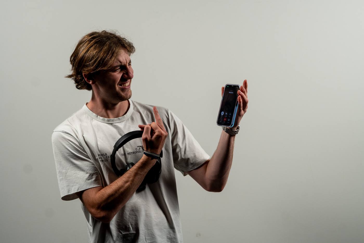 Jeune homme souriant avec un téléphone, fond gris clair